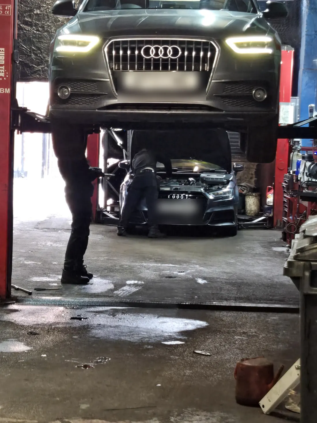 One Audi up on the lift, a second below it with someone working under its bonnet