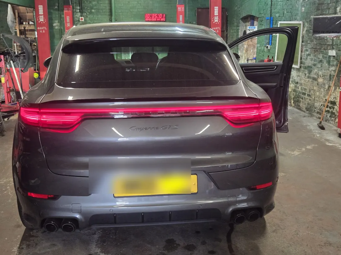 A grey Porsche Macan in the workshop with its driver’s door open